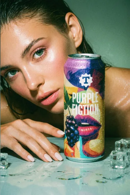 Model holding a Purple Fiction beer can with fruit graphics, beverage branding by Renuvo Design Inc.