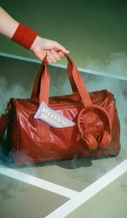 WELLBAR red duffel bag on a tennis court, brand campaign by Renuvo Design Inc.